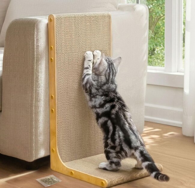 Kitten scratching an L-shaped cardboard scratching pad leaning against a sofa, manufacturer product photo